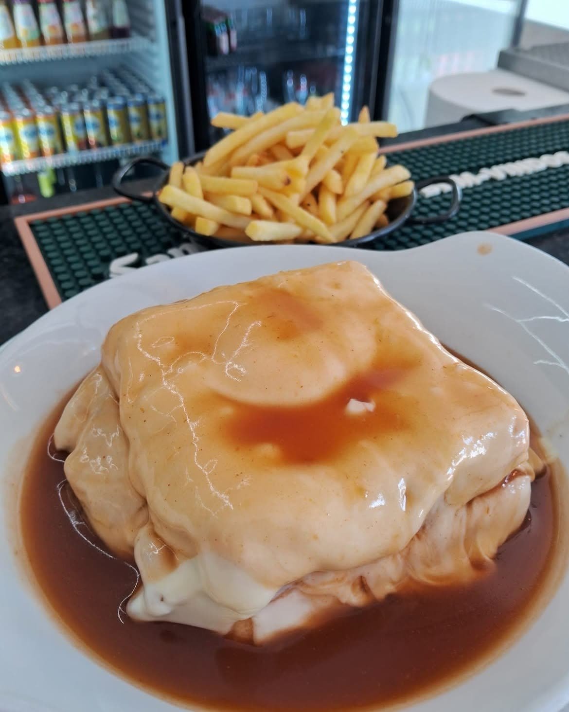 Francesinha von Capa Negra, serviert mit einer Schüssel Pommes frites