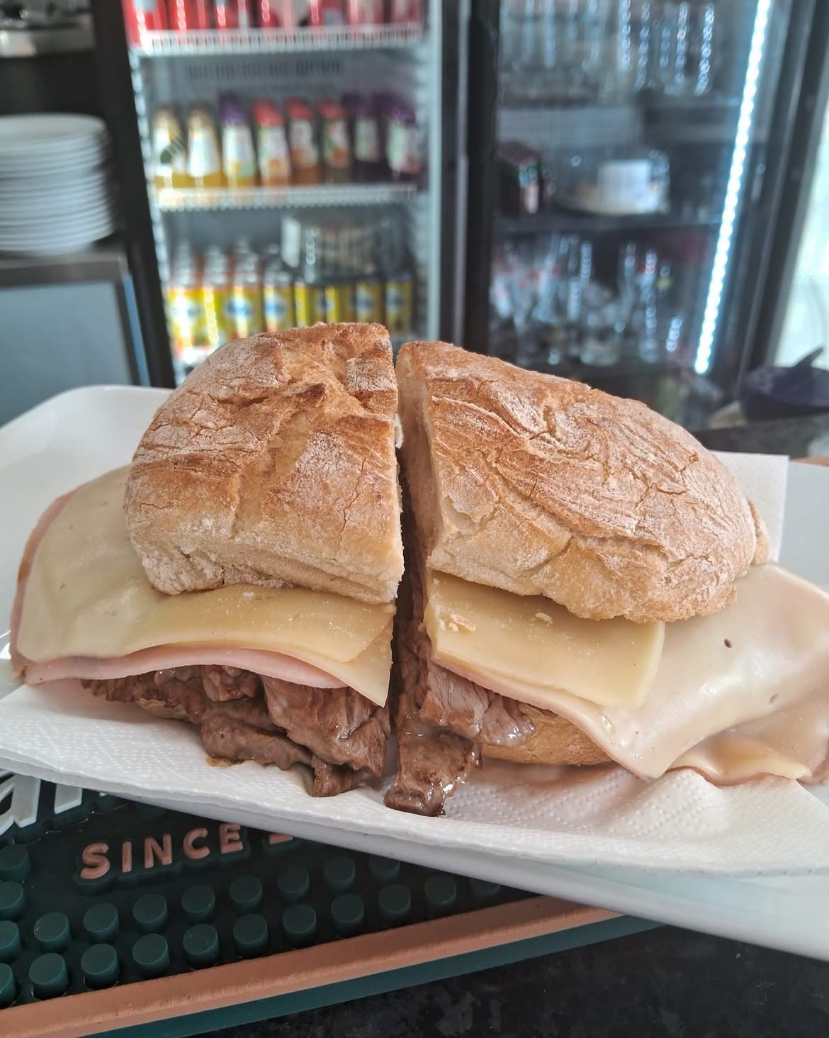 Gemischtes Steaksandwich im Wasserbrötchen, aufgeschnitten, mit Steak, Käse und Schinken